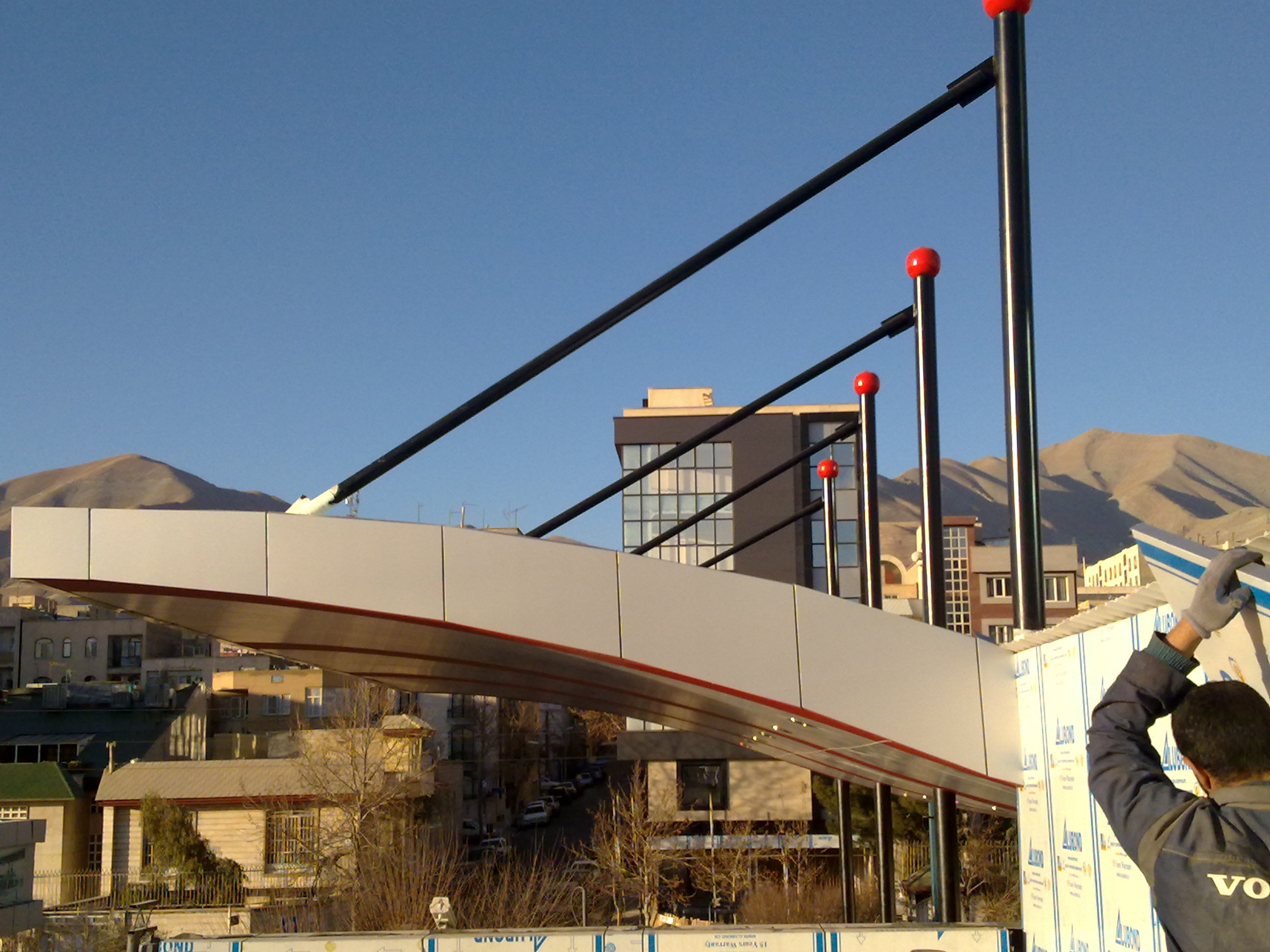 Installation phase — ACP panel fitting in progress with Tehran mountains visible